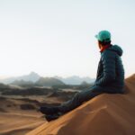 a person sitting on top of a sand dune